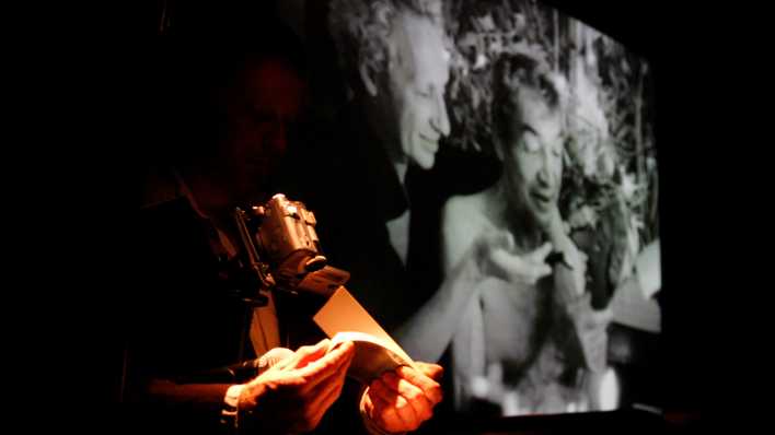 Volker Gerling blaettert ein Daumenkino unter einer Videokamera durch, per Beamer wird die Vorstellung auf eine Leinwand projiziert.