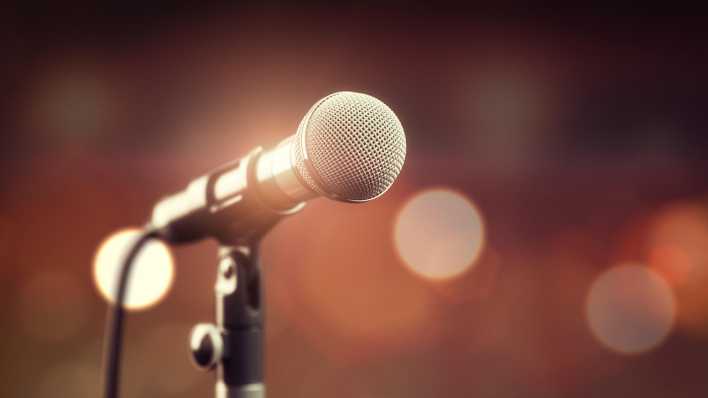 Ein Mikrofon steht auf einer Bühne.