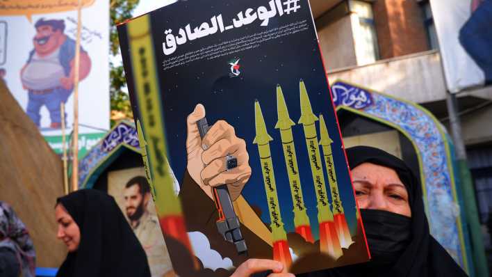 Eine Anhängerin der iranischen Regierung hält in Teheran ein israelfeindliches Plakat hoch (Bild: picture alliance/ZUMAPRESS.com/Rouzbeh Fouladi)