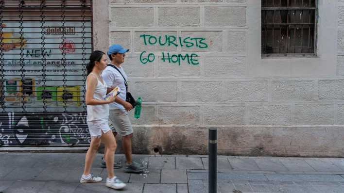 Symbolfoto: "Tourists go home" steht an einer Hauswand in Barcelona