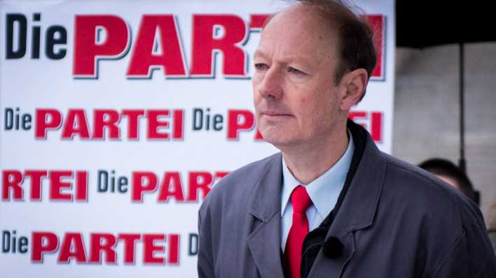 Martin Sonneborn vor einem Plakat von "Die Partei"