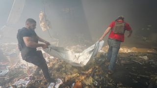 Rettungskräfte tragen eine Leiche nach dem Einschlag einer russischen Rakete in Charkiw (Bild: picture alliance/dpa/AP/Andrii Marienko)