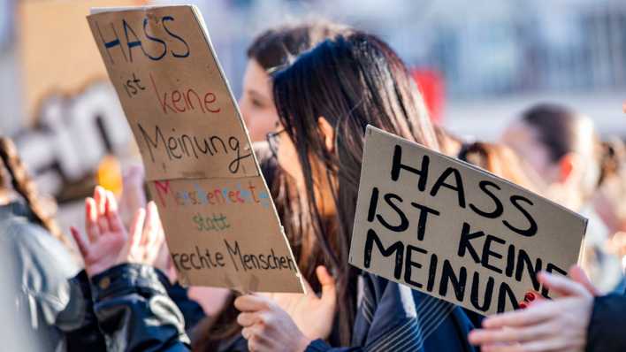 Eine Demonstrantin in Dresden hält ein Schild mit der Aufschrift "Hass ist keine Meinung" hoch.