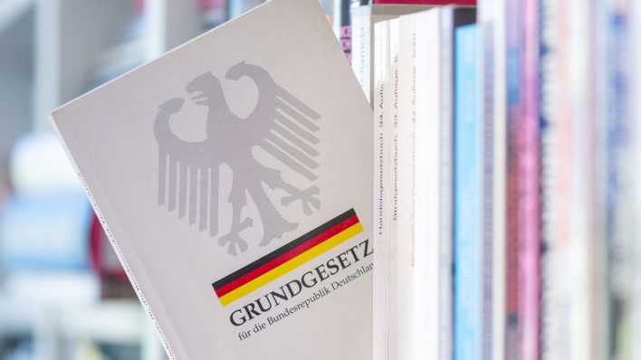 Ein Grundgesetz steckt in einem Bücherregal (Bild: picture alliance/dpa/Hendrik Schmidt)
