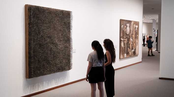 Zwei Frauen betrachten ein Bild in einer Ausstellung.