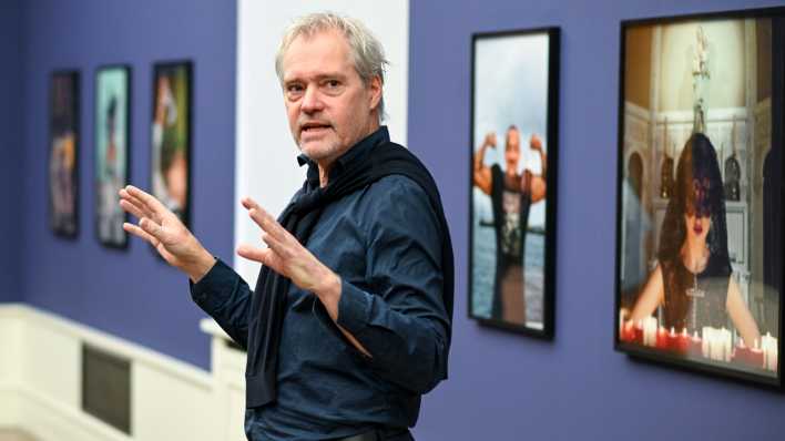 Vor Fotos der Ausstellung "Helmut Newton.Brands" erklärt Matthias Harder, Direktor der Helmut Newton Stiftung