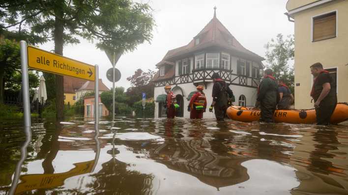 Mit einem Schlauchboot gehen Feuerwehr und Wasserrretter im bayerischen Wertingen in eine überflütete Straße (Bild: picture alliance/dpa/Stefan Puchner)