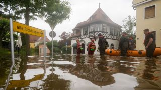 Mit einem Schlauchboot gehen Feuerwehr und Wasserrretter im bayerischen Wertingen in eine überflütete Straße (Bild: picture alliance/dpa/Stefan Puchner)