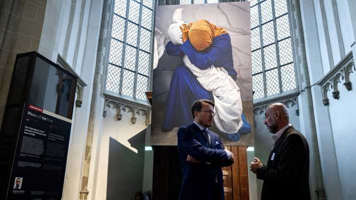 Zwei Männer unterhalten sich vor dem "Photo of the Year", das in der World Press Photo Ausstellung hängt.