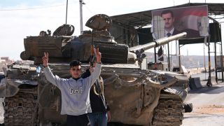 Oppositionelle stehen neben einem Panzer der Regierungstruppen, der auf einer Landstraße zurückgelassen wurde.