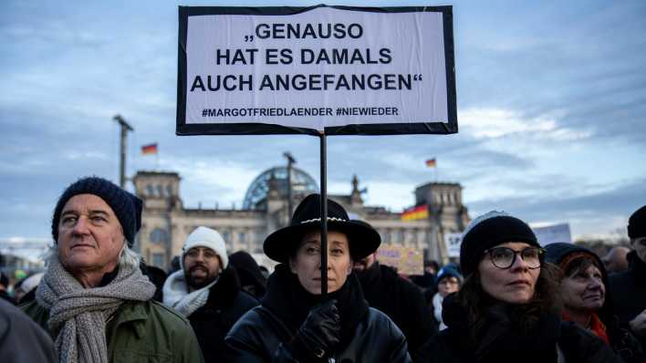 Eine Demonstrantin hält vor dem Bundestag ein Schild mit der Aufschrift "Genauso hat es damals auch angefangen" hoch.