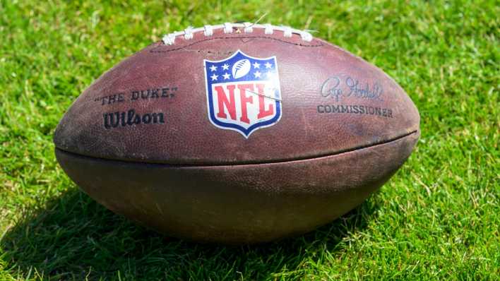 Ein Football der NFL liegt auf einem Rasen.