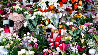 Blumen und Kerzen liegen vor der Johanniskirche in der Nähe des Weihnachtsmarkts in Magdeburg.