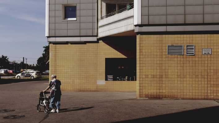 Eine alte Frau mit Rollator vor einem Wohnblock in Marzahn