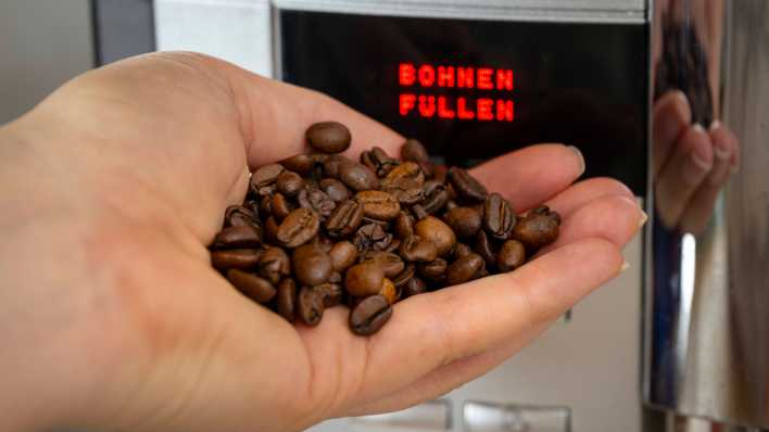 Kaffeebohnen in der Hand, Kaffeevollautomat mit Schrift "Bohnen Füllen"