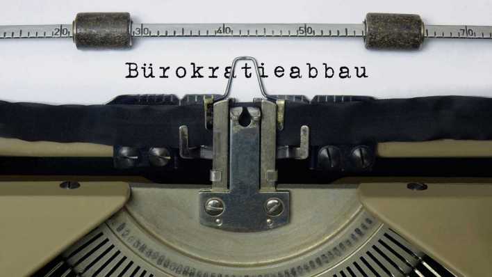 Auf dem Papier in einer Schreibmaschine steht der Schriftzug Bürokratieabbau (Bild: picture alliance/ZB/Sascha Steinach)
