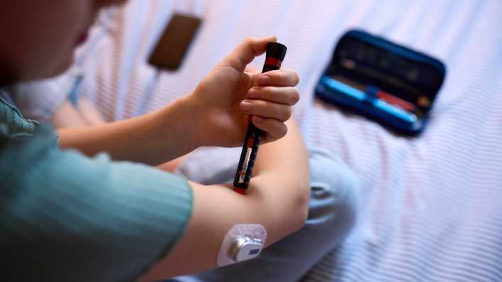 Ein Kind spritzt sich mit einem Pen Insulin in den Oberarm