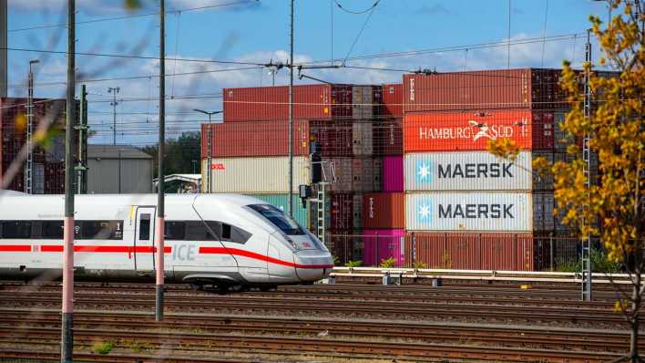 Ein ICE-Zug fährt an gestapelten Containern am Berliner Westhafen vorbei.