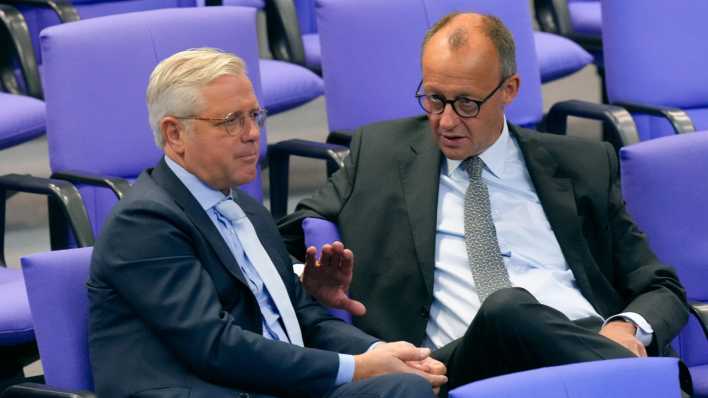 Norbert Röttgen und Friedrich Merz unterhalten sich auf Stühlen im Bundestag.
