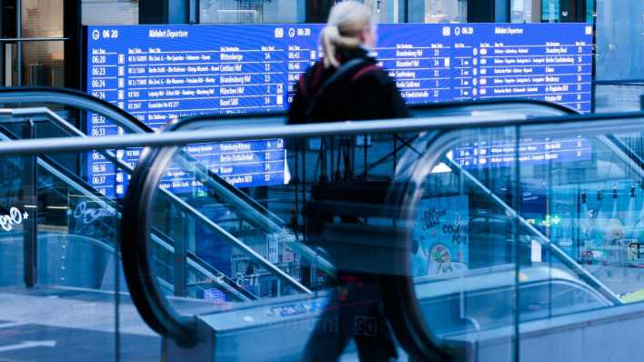 Eine Reisende geht im Berliner Hauptbahnhof an einer Anzeigetafel vorbei.