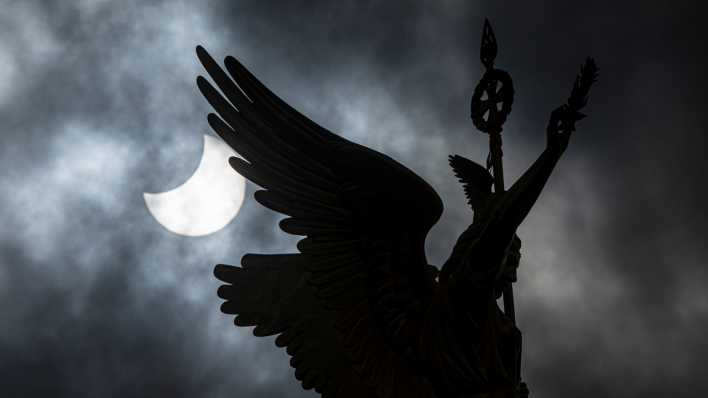 Die Sonne wird bei einer Partiellen Sonnenfinsternis teilweise vom Mond verdeckt, im Vordergrund die "Goldelse" der Siegessäule.