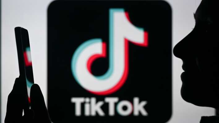 Junge Frau mit Smartphone und TikTok-Logo