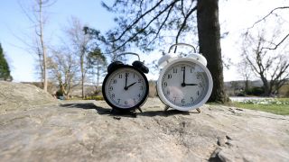 Ein Wecker zeigt zwei Uhr und der andere drei Uhr. Die Uhren werden am Sonntag den 30.03.2025 auf Sommerzeit umgestellt.
