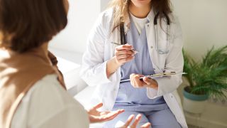 Eine Hausärztin spricht mit einer Patientin und macht sich Notizen.