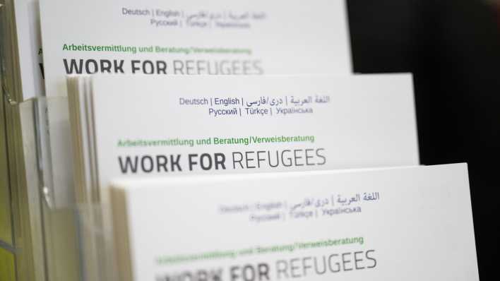 Am ehemaligen Flughafen Tegel steht ein Aufsteller mit Informationsmaterial mit der Aufschrift "Work for refugees".