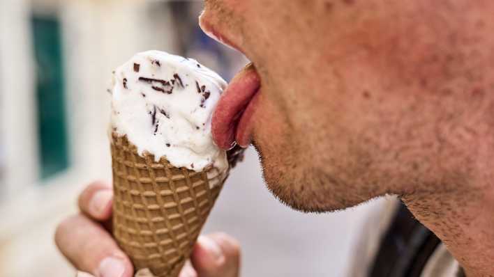 Nahaufnahme eines Mannes, der ein Stracciatella-Eis in einer Waffel im Sommer schleckt.