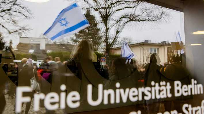 Eine Israel-Flagge spiegelt sich bei einem stillen Protest einer Initiative für die Sicherheit jüdischer Studierender in einer Scheibe der Freien Universität Berlin.