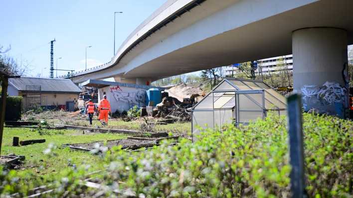 Mitarbeiter der Autobahn GmbH gehen durch Kleingärten, die wegen des Abriss der maroden Ringbahnbrücke der A100 weichen müssen.