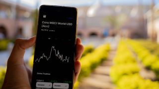 Ein Nutzer hält eine Smartphone-App mit dem Kursverlauf des MSCI World.
