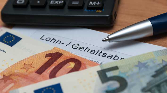 Ein 10- und ein 5-Euro-Schein liegen auf einer Lohnabrechnung.
