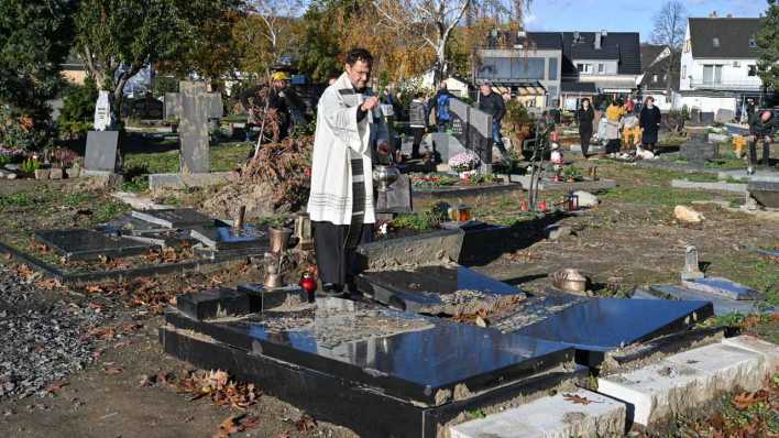 ARCHIV: Jörg Meyrer, Pfarrer der Pfarreiengemeinschaft Bad Neuenahr-Ahrweiler, segnet an Allerheiligen beschädigte Gräber auf dem nach der Flutkatastrophe zerstörten Friedhof in Ahrweiler am 1. November 2021 (Bild: picture alliance/KNA/Harald Oppitz)