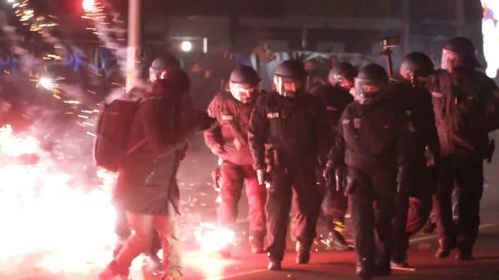 Polizisten stehen in der Silvesternacht zwischen brennendem Feuerwerk. Polizisten stehen in der Silvesternacht zwischen brennendem Feuerwerk.