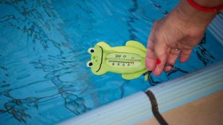 Eine Badegast misst am ersten Tag der Freibadsaison im Prinzenbad die Wassertemperatur (Bild: picture alliance/dpa/Jörg Carstensen)