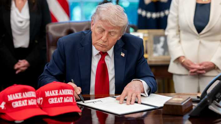 Donald Trump unterzeichnet ein Dekret an seinem Schreibtisch im Oval Office.