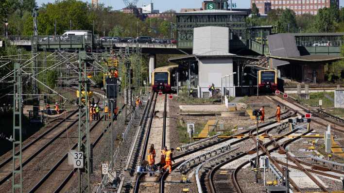 Bauarbeiter gehen über Bahngleise am S-Bahnhof Westend. Nach dem Abriss der Ringbahn- und der Westendbrücke soll die Ringbahn ab Montag wieder fahren.