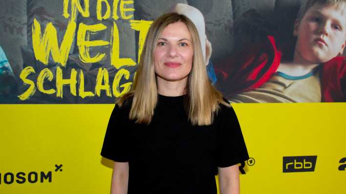 Constanze Klaue (Regisseurin) vor dem Filmplakat zu "Mit der Faust in die Welt schlagen" (Bild: picture alliance / PIC ONE | Christian Behring)