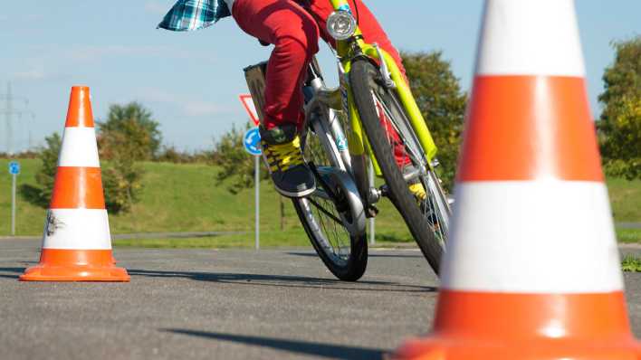 Kind übt mit dem Fahrrad Slalom fahren auf dem Verkehrsübungsplatz