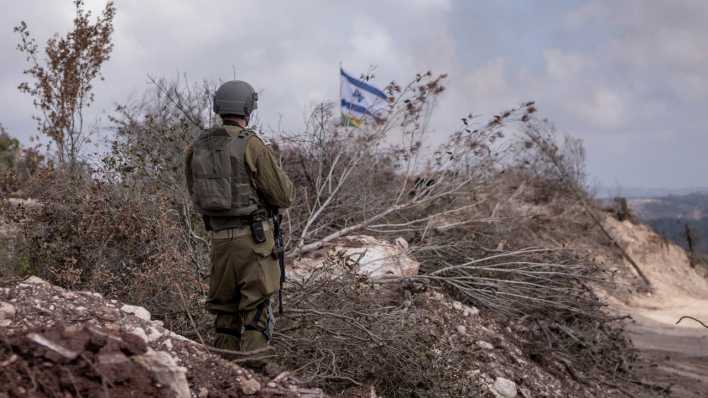 Ein israelischer Soldat steht vor einer wehenden Israel-Flagge im südlibanesischen Dorf Naqoura an der Grenze zu Israel.