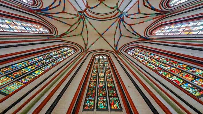 Licht fällt durch die bunten Scheiben der historischen Bleiglasfenster in der Marienkirche (Bild: picture alliance/dpa/Patrick Pleul)