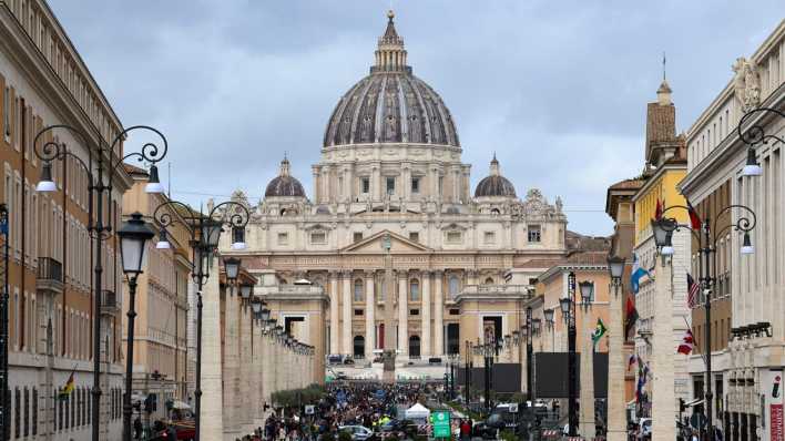 Blick auf den Petersdom über die Via della Conciliazione, tausende Menschen gehen in Richtung des Vatikans.