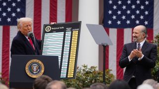 US-Präsident Donald Trump hält eine Tafel mit Zöllen vor US-Fahnen (Bild: picture alliance / AP | Mark Schiefelbein)