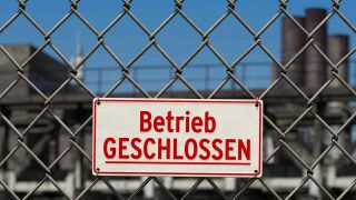 Symbol Wirtschaftskrise: Hinweisschild an Maschendrahtzaun vor Betriebsgelände: Betrieb geschlossen (Bild: IMAGO/IlluPics)