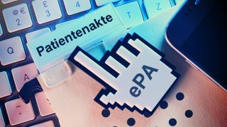Computercursor zeigt auf Patientenakte auf einer Computertastatur