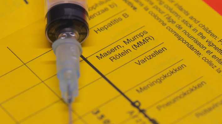 Impfpass mit Eintrag Menningokokken und Spritze