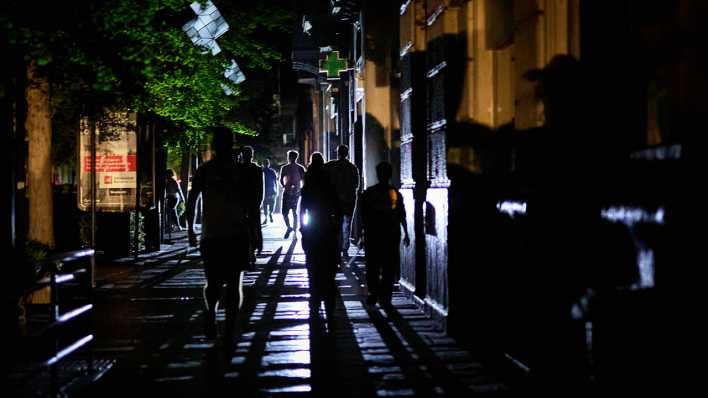 Menschen gehen in Granada während eines Stromausfalls in der Dunkelheit eine Straße entlang.