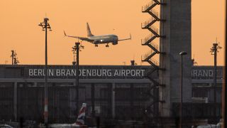 Ein Flugzeug landet zum Sonnenaufgang am Flughafen Berlin Brandenburg (BER).